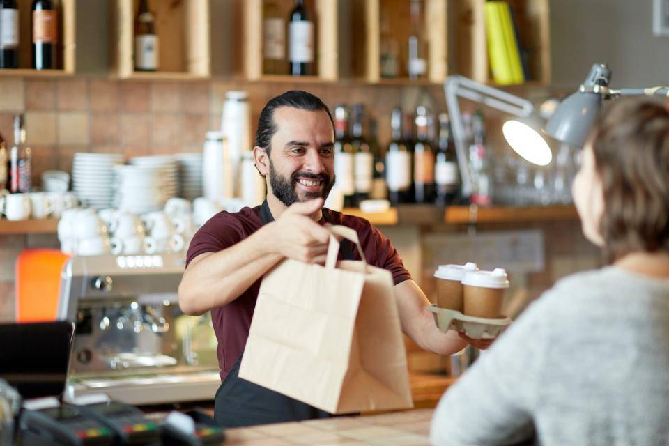 A shop owner hands a bag to a customer